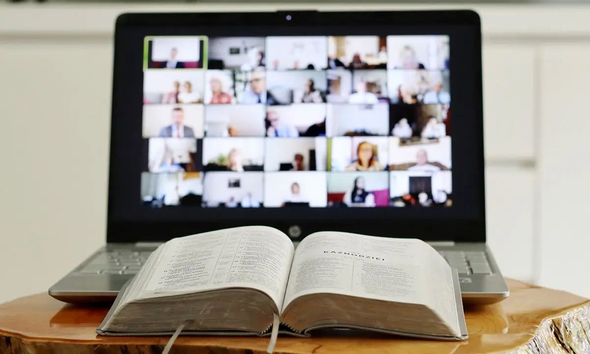 Imagen que muestra un libro en primer plano y un ordenador al fondo con una sesión grupal online para la sección del botón de formación online de Somatic Experiencing